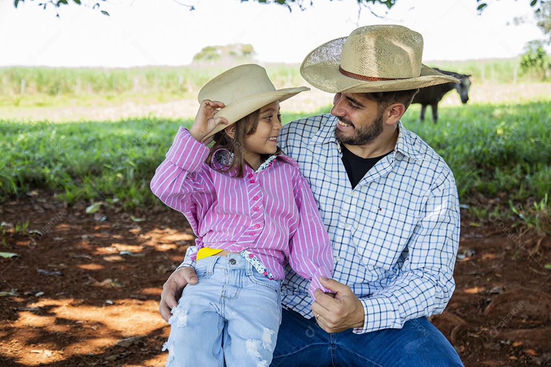 Garotinha ao lado de seu pai fazendeiro sobre fazenda