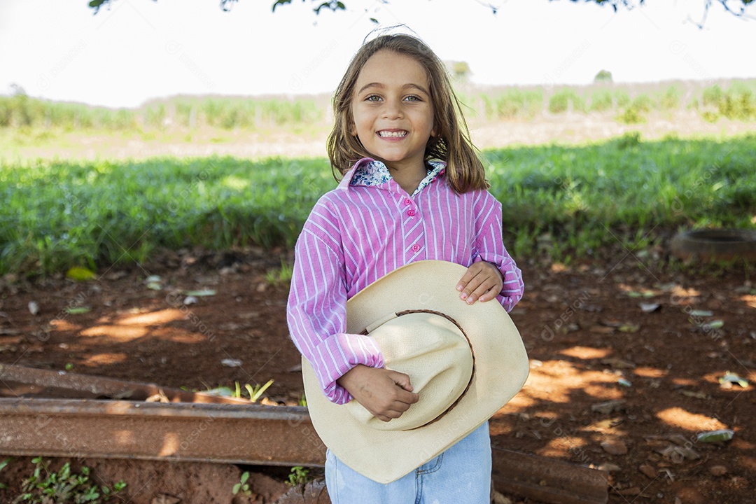 Linda garotinha feliz e sorridente brincando sobre terreno de uma fazenda