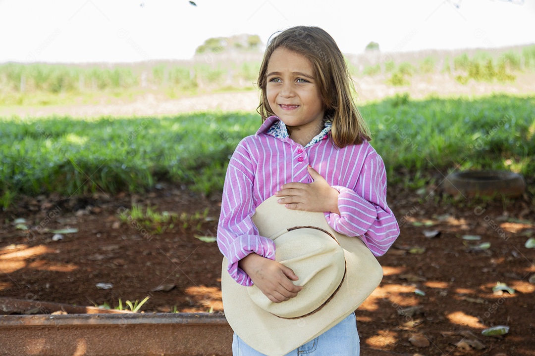 Linda garotinha feliz e sorridente brincando sobre terreno de uma fazenda