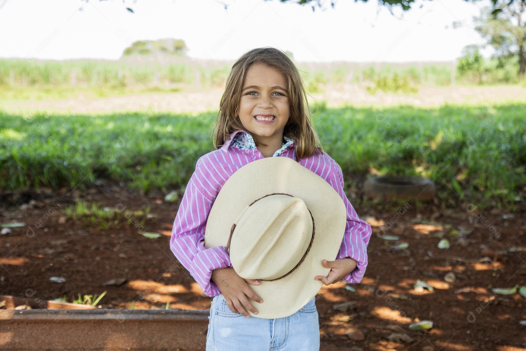 Linda garotinha feliz e sorridente brincando sobre terreno de uma fazenda