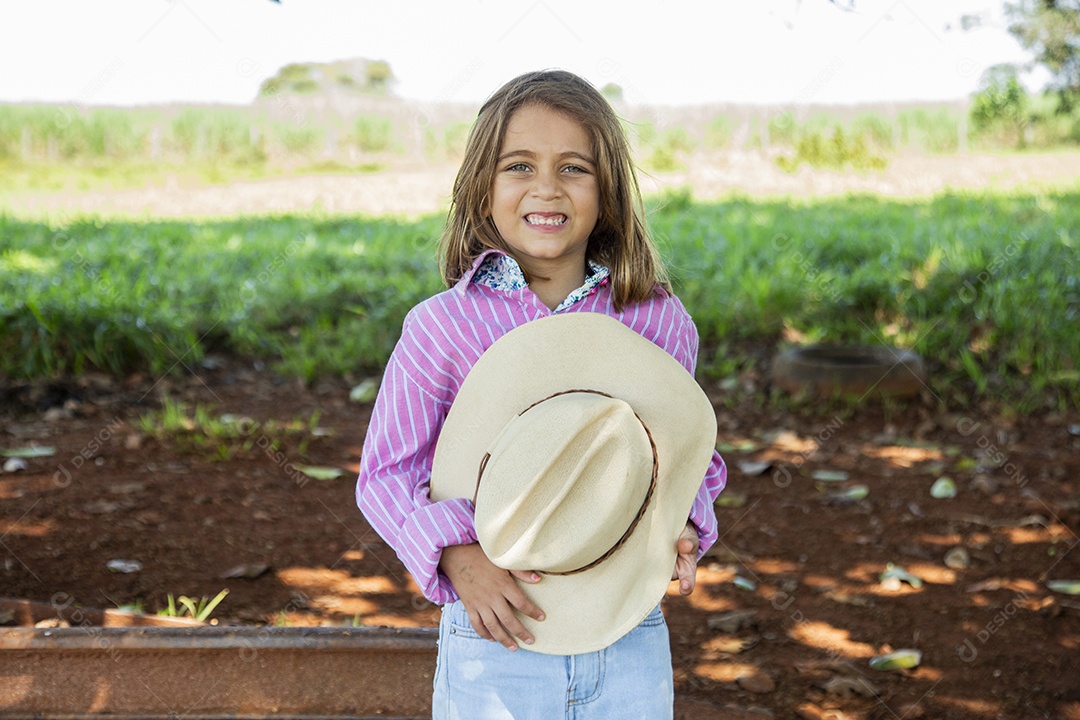 Linda garotinha feliz e sorridente brincando sobre terreno de uma fazenda