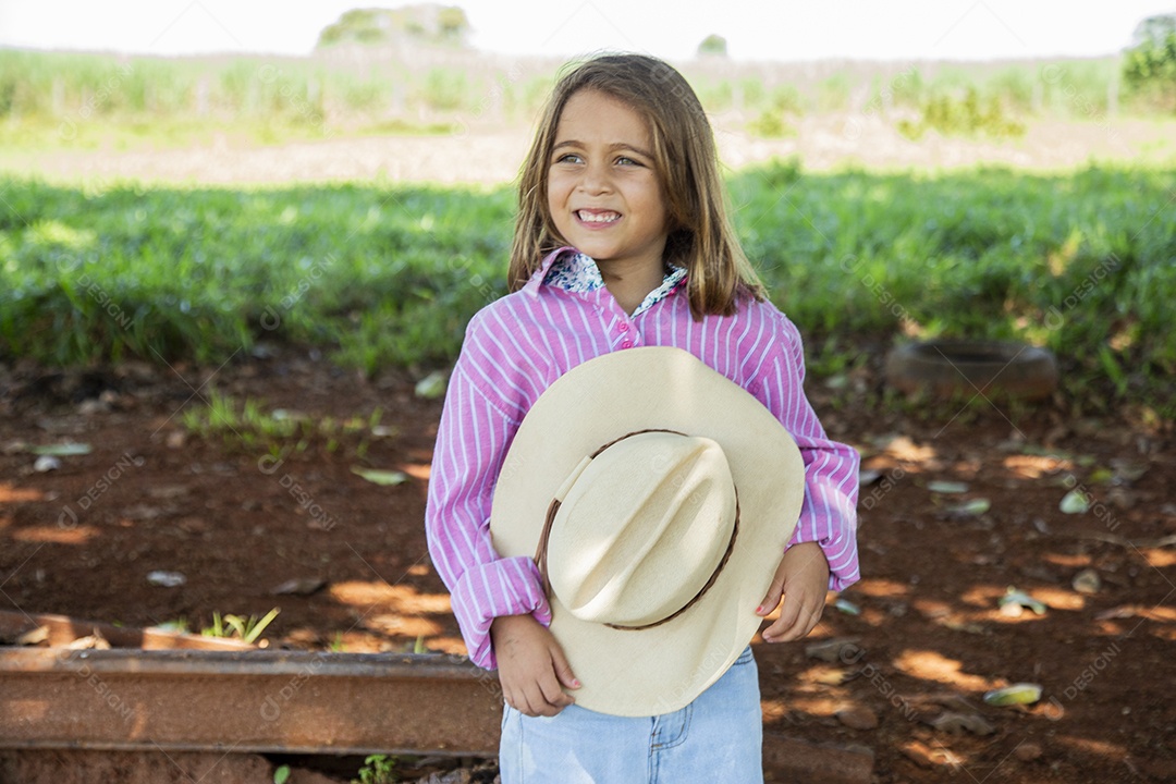 Linda garotinha feliz e sorridente brincando sobre terreno de uma fazenda