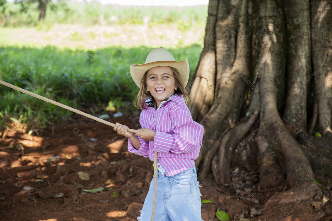 Linda garotinha feliz e sorridente brincando sobre terreno de uma fazenda