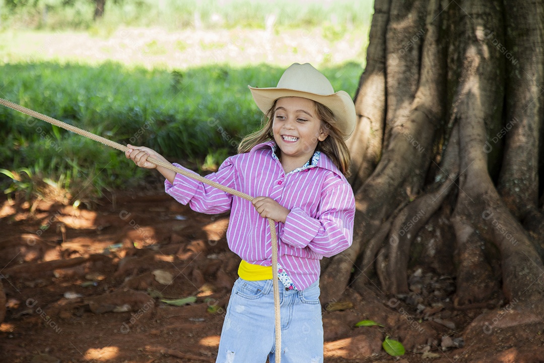 Linda garotinha feliz e sorridente brincando sobre terreno de uma fazenda