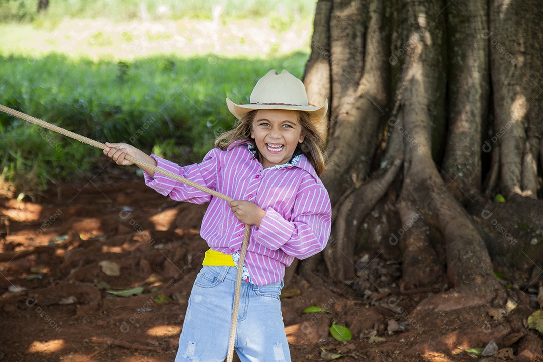 Linda garotinha feliz e sorridente brincando sobre terreno de uma fazenda