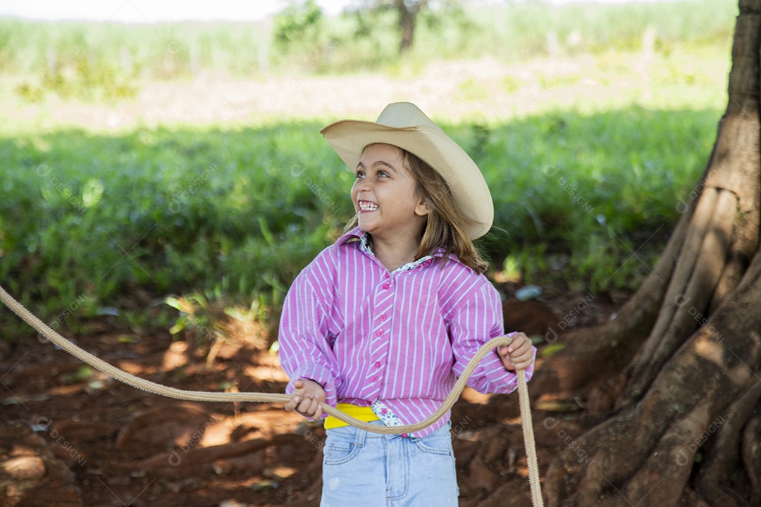 Linda garotinha feliz e sorridente brincando sobre terreno de uma fazenda