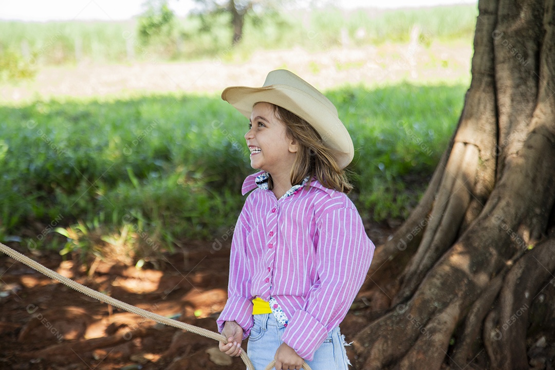 Linda garotinha feliz e sorridente brincando sobre terreno de uma fazenda