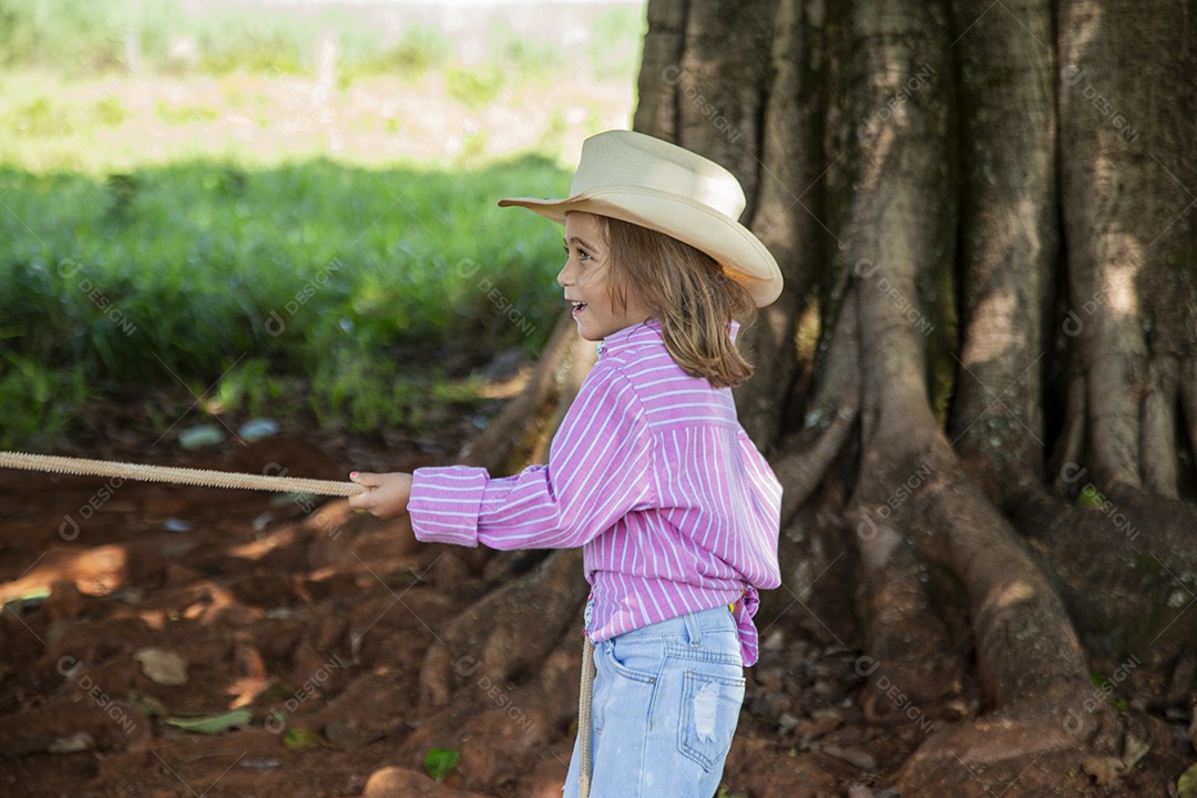 Linda garotinha feliz e sorridente brincando sobre terreno de uma fazenda