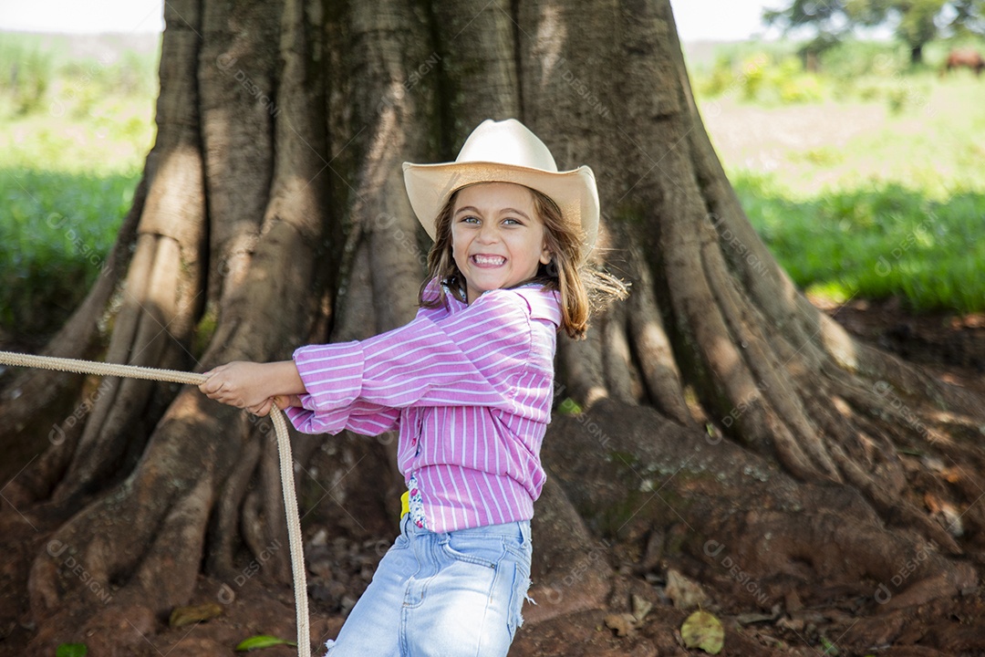 Linda garotinha feliz e sorridente brincando sobre terreno de uma fazenda