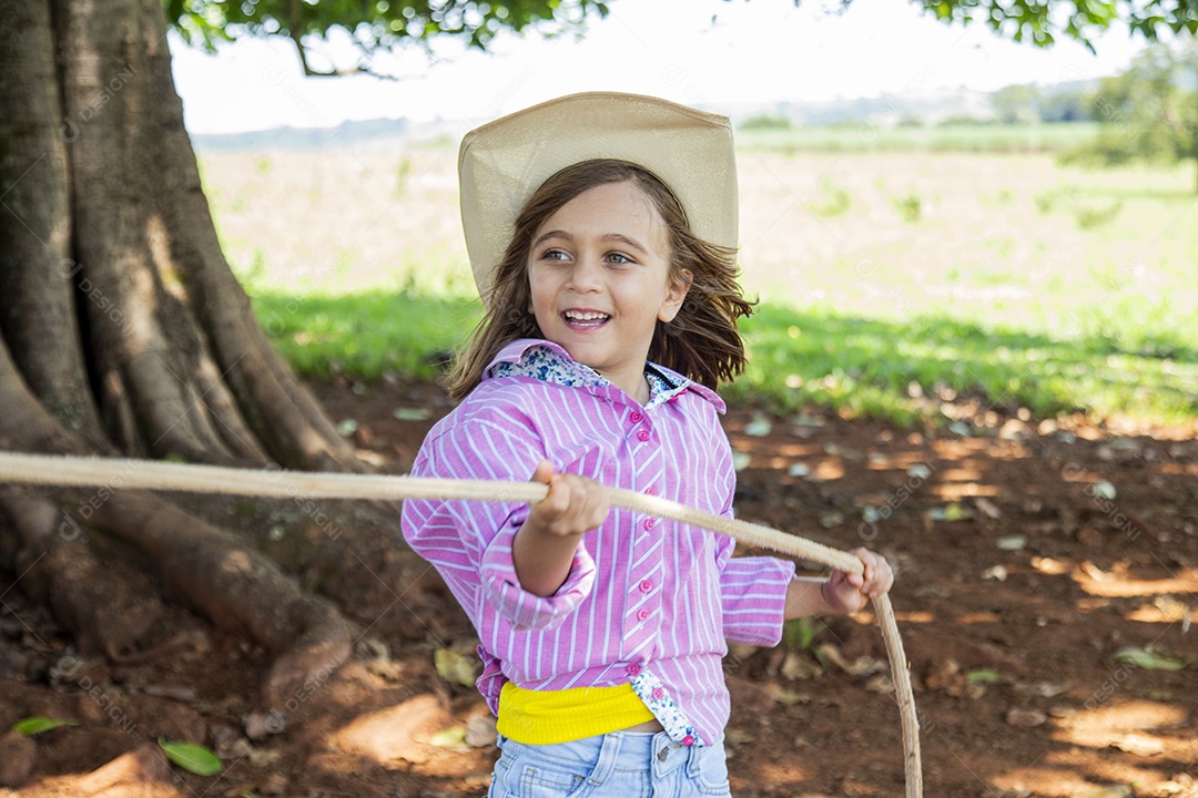 Linda garotinha feliz e sorridente brincando sobre terreno de uma fazenda