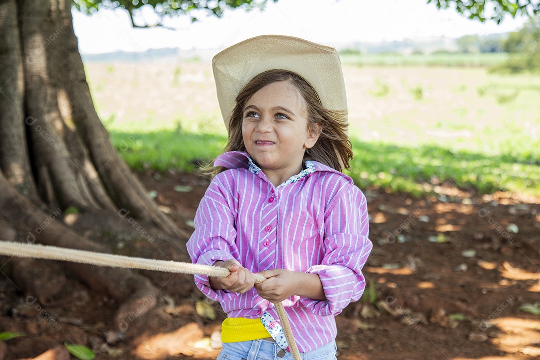 Linda garotinha feliz e sorridente brincando sobre terreno de uma fazenda