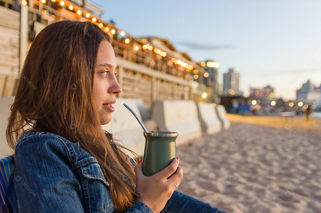 Uma linda mulher tomando chimarrão na beira da praia