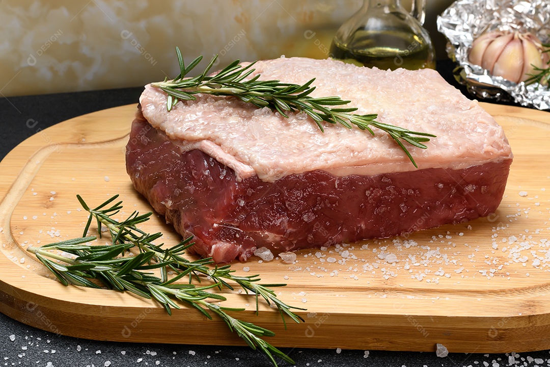 Carne bovina e alecrim sobre a tábua de madeira