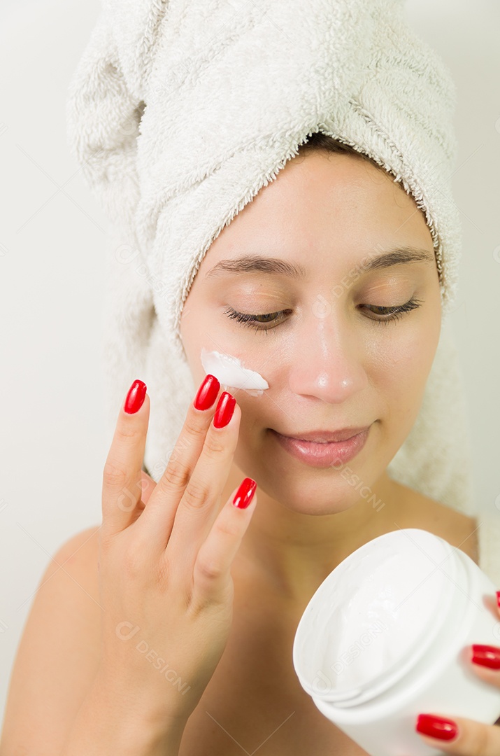 Jovem mulher passando creme facial para hidratação de pele