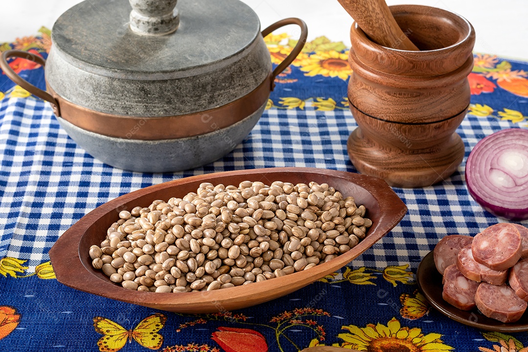 Tigela com feijão outra de calabresa e panela para preparação de feijoada