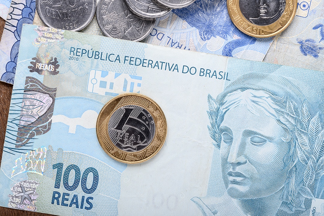 Dinheiros em notas e moedas sobre mesa de madeira