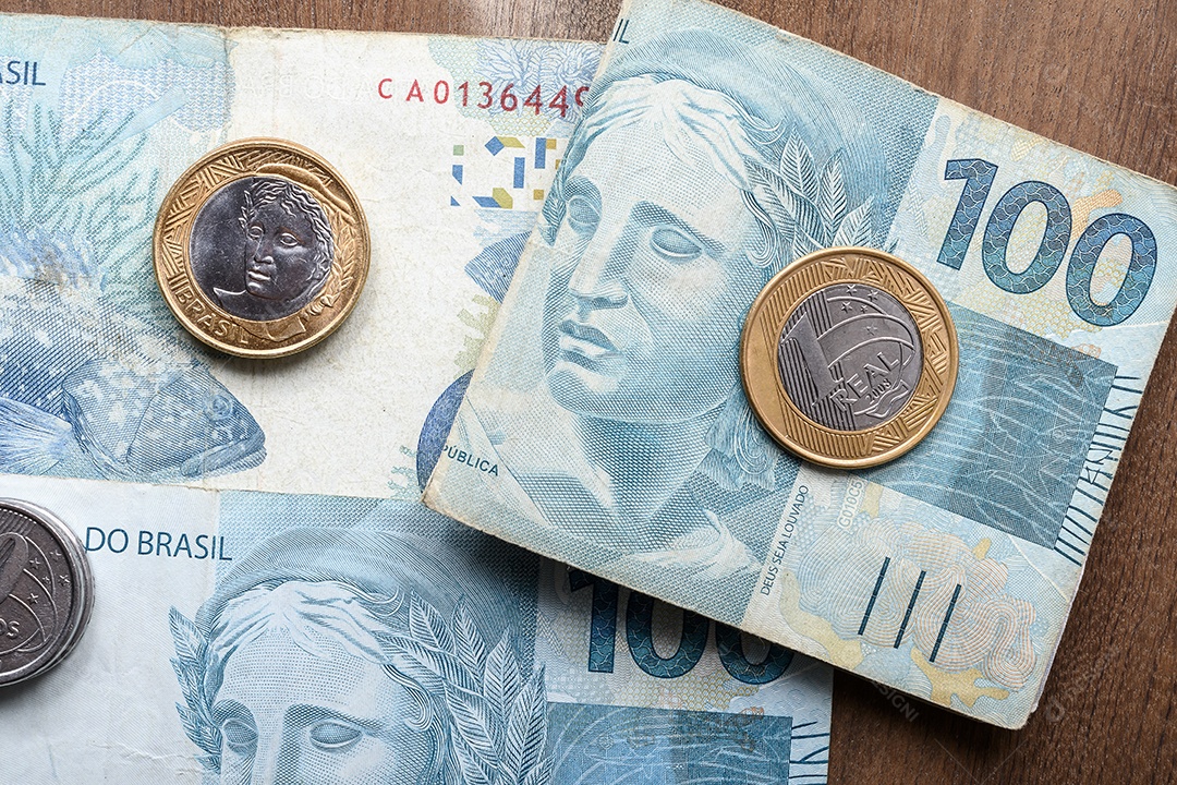 Dinheiros em notas e moedas sobre mesa de madeira