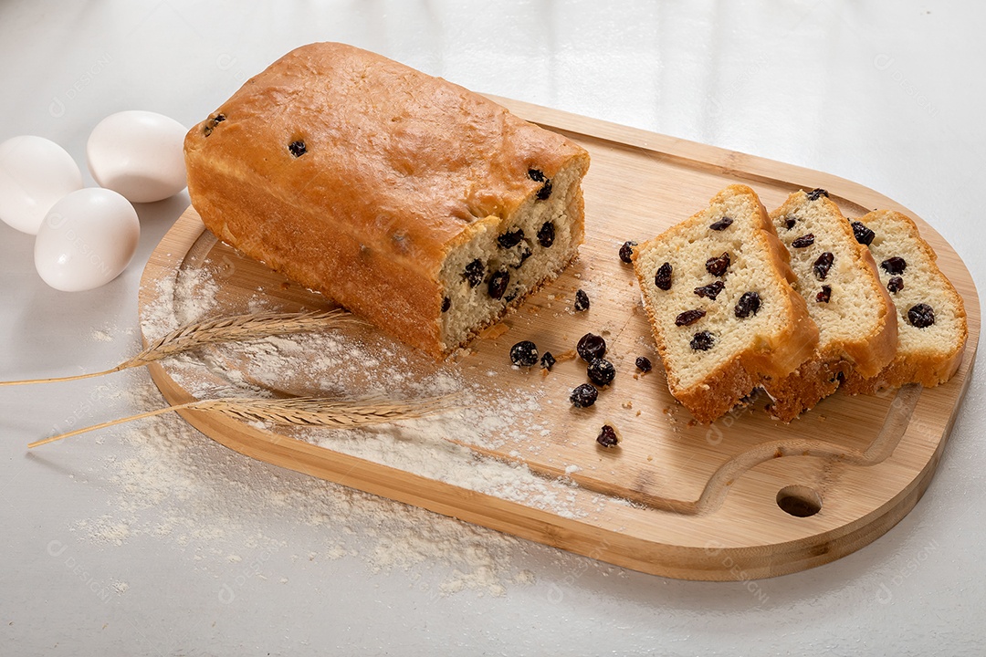 Pão caseiro de passas com fatias cortadas sobre uma tábua