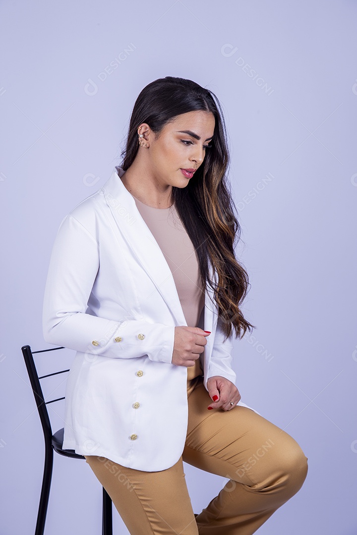 Linda mulher sentada em uma cadeira usando blazer branco sobre fundo isolado