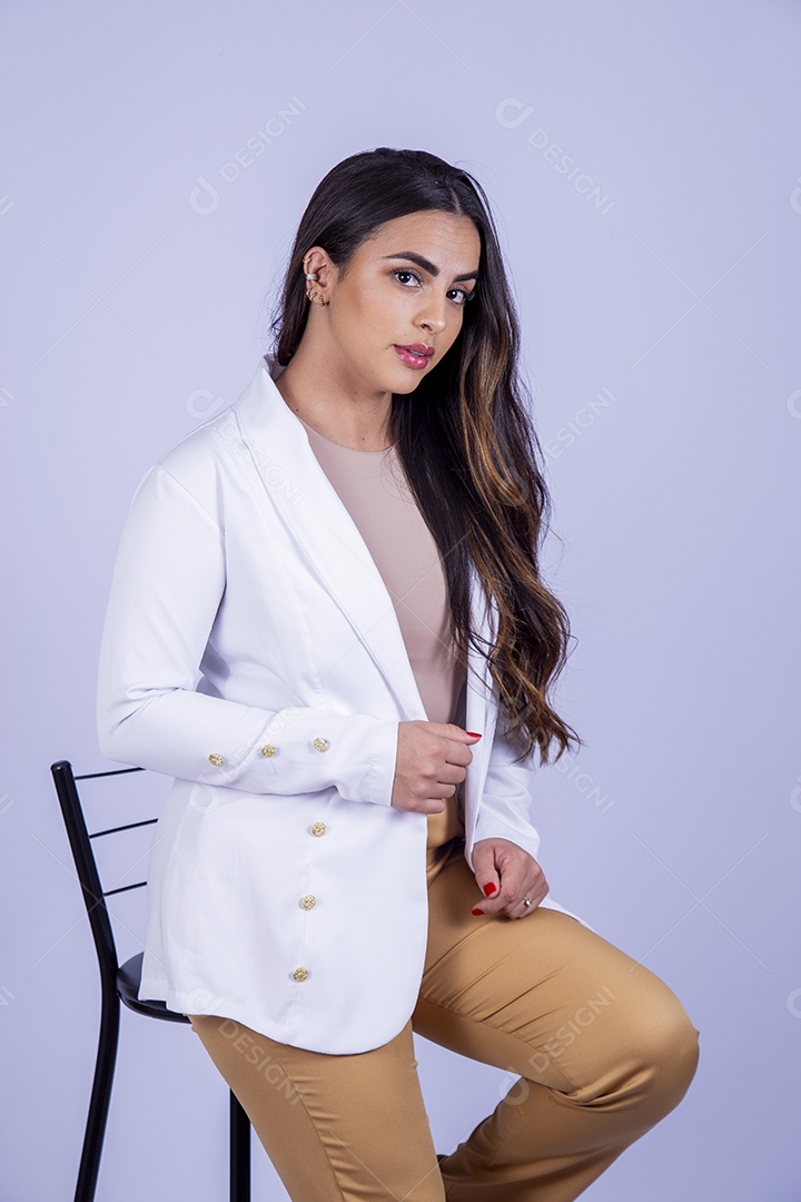 Linda mulher sentada em uma cadeira usando blazer branco sobre fundo isolado