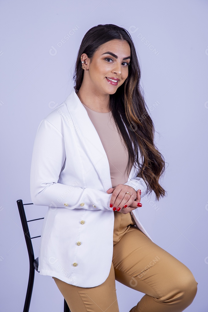 Linda mulher sentada em uma cadeira usando blazer branco sobre fundo isolado