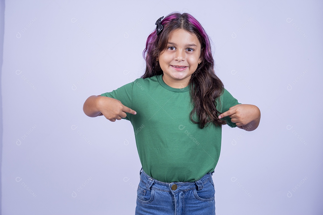Linda menina apontando para a camisa sobre fundo isolado
