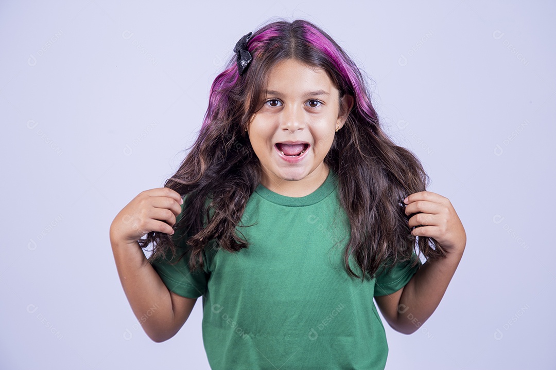 Linda garotinha de boca aberta passando a mão no cabelo.