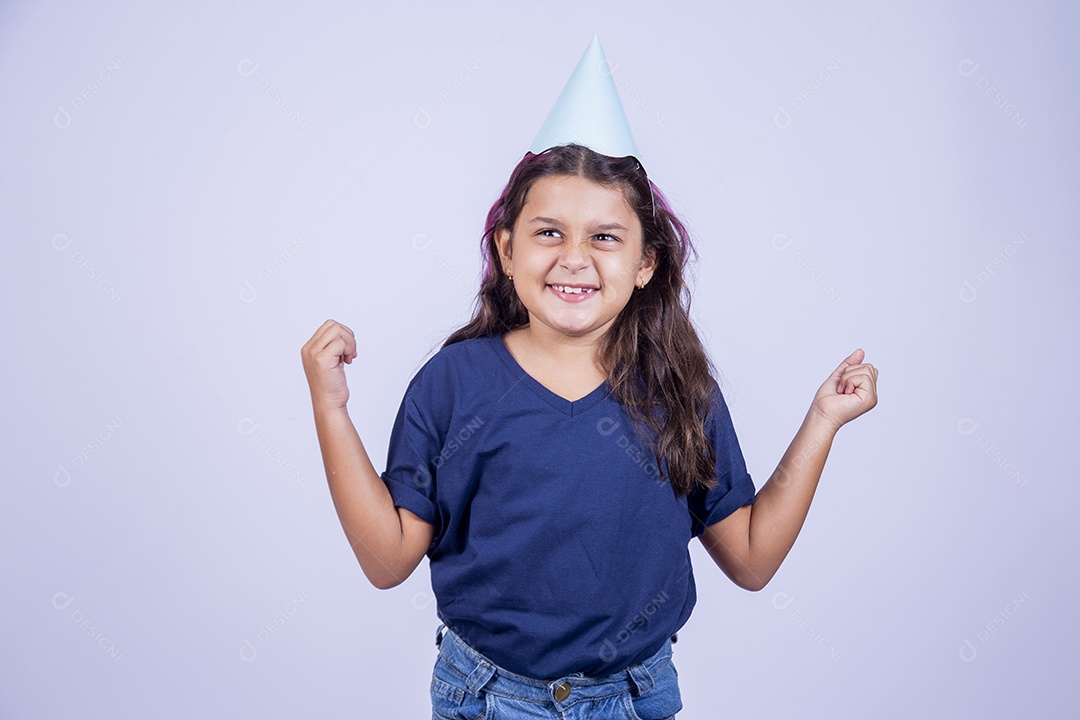 Garotinha com expresssão de comemoração usando chapeu de festa.