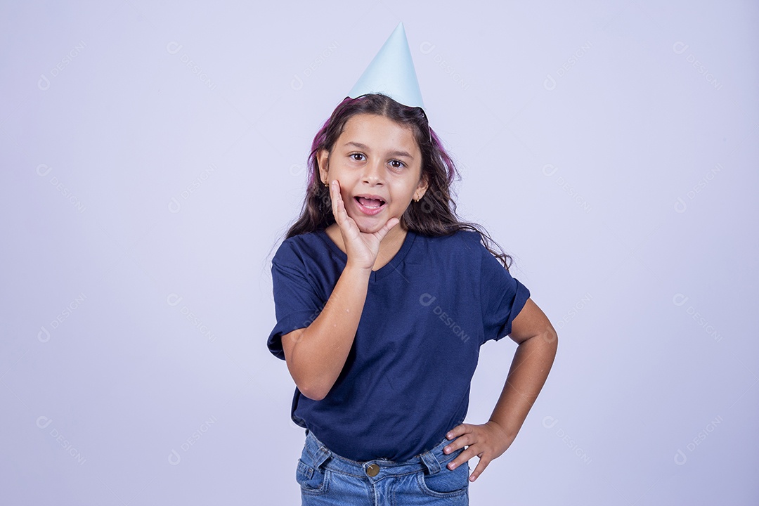 Criança com a mão sobre a boca usando chapeu de festa.