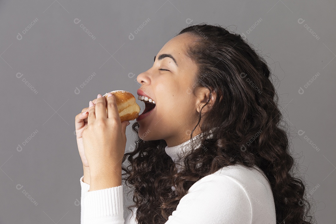 Linda mulher comendo sonho de padaria sobre fundo isolado