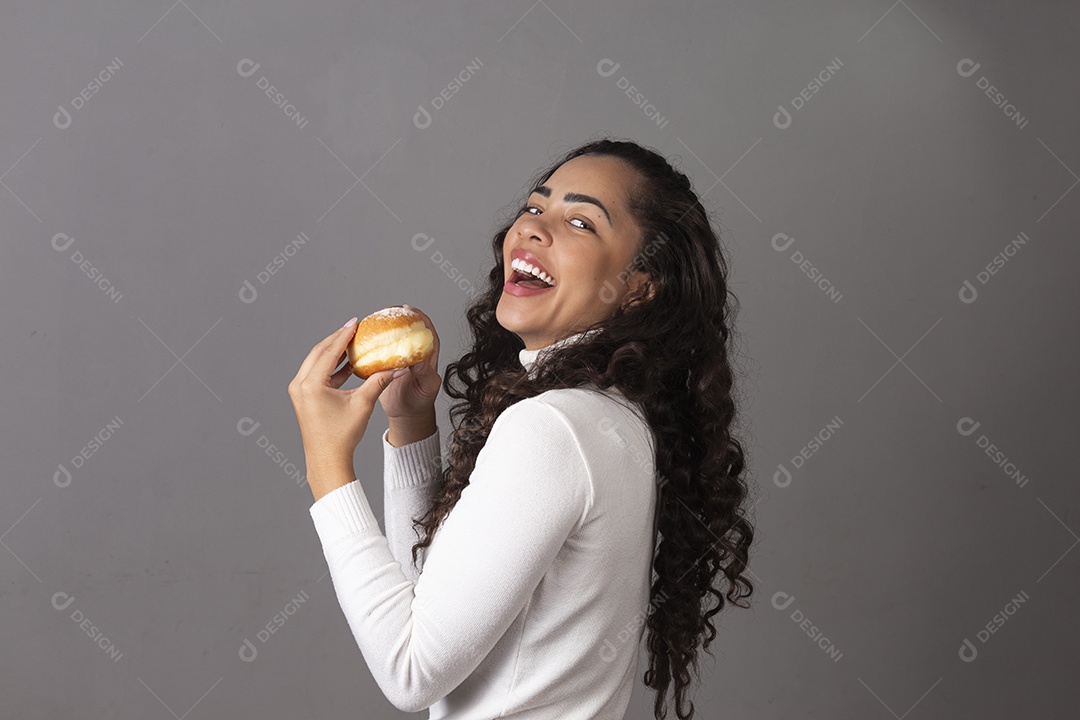 Linda mulher sorridente comendo sonho de padaria sobre fundo isolado