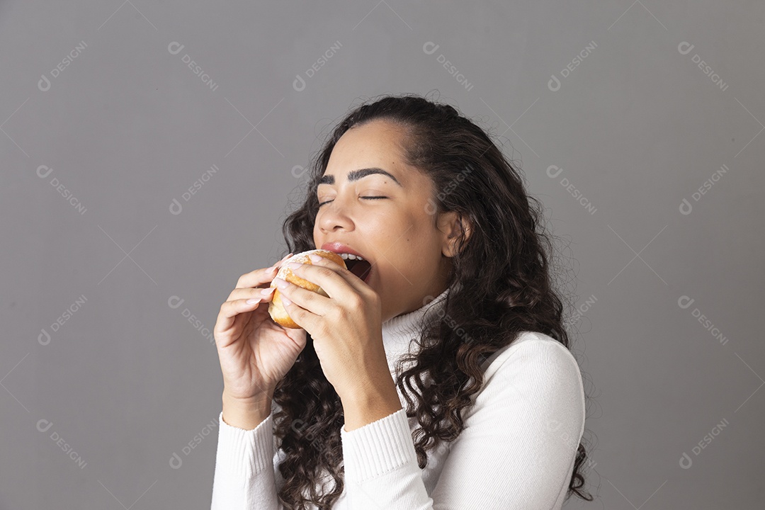 Linda mulher comendo sonho de padaria sobre fundo isolado