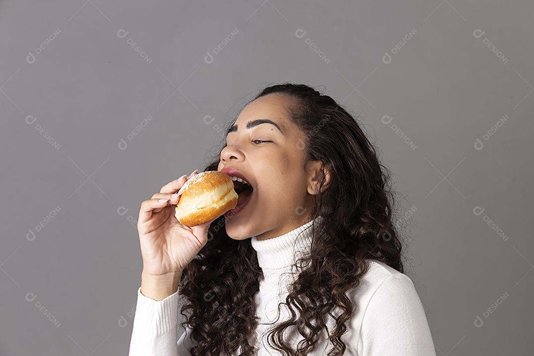 Linda mulher comendo sonho de padaria sobre fundo isolado