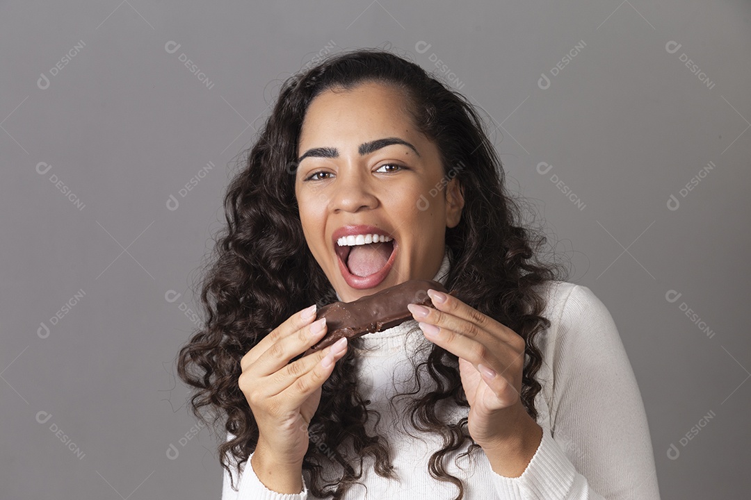 Linda mulher sorridente comendo chocolate sobre fundo isolado
