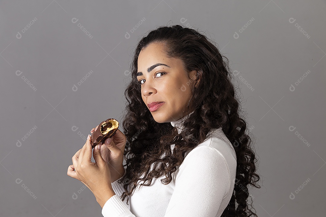 Linda mulher comendo chocolate sobre fundo isolado