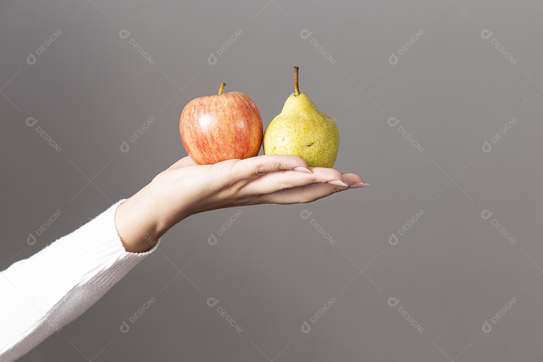 Mãos de pessoa segurando maçã e pera