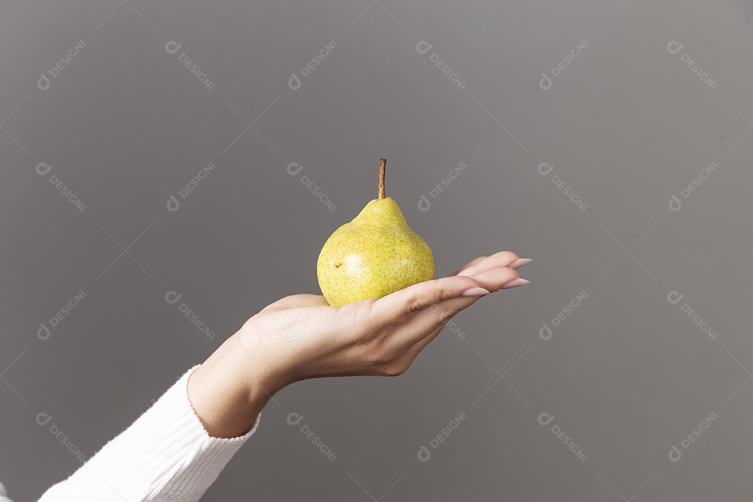 Mão segurando uma pera sobre fundo isolado