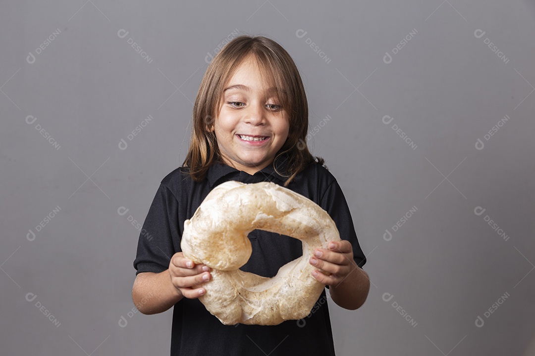 Criança sorridentes segurando biscoito rosca de polvilho sobre fundo isolado