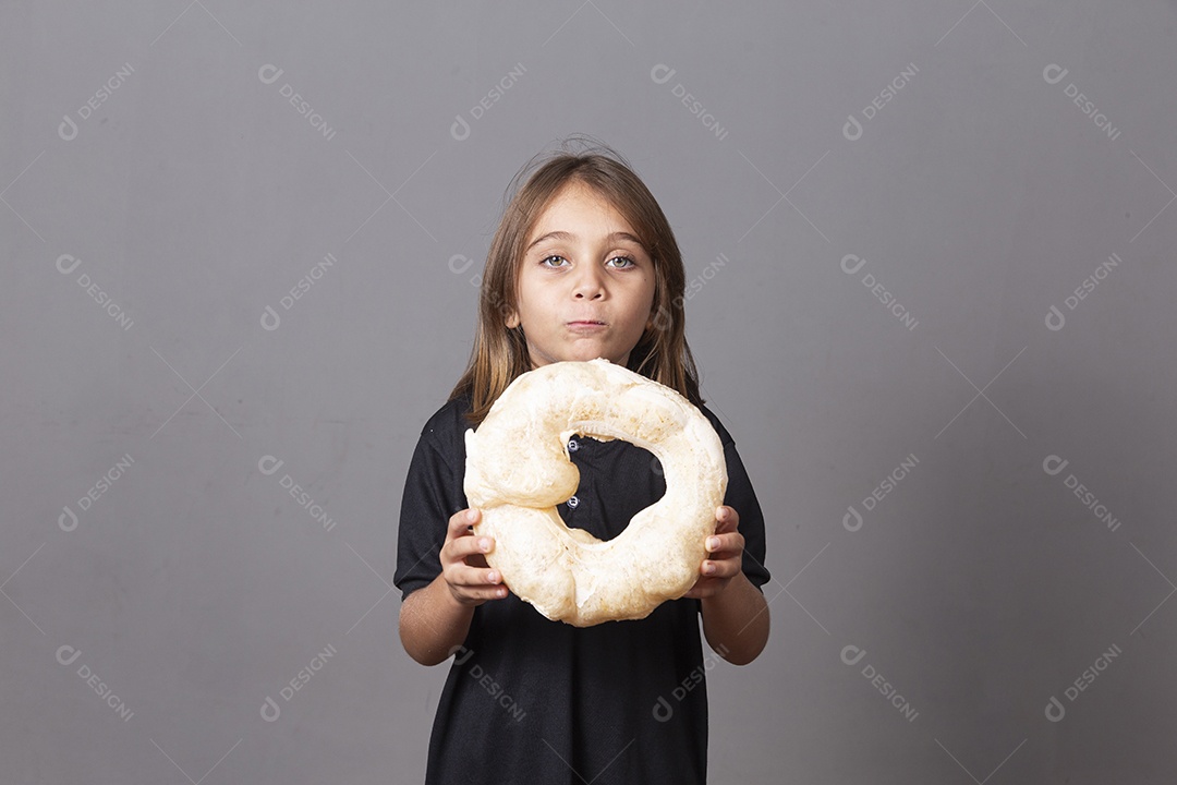 Criança segurando biscoito rosca de polvilho sobre fundo isolado