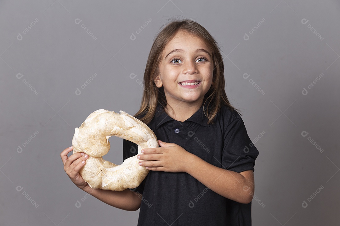 Criança sorridente segurando biscoito rosca de polvilho sobre fundo isolado
