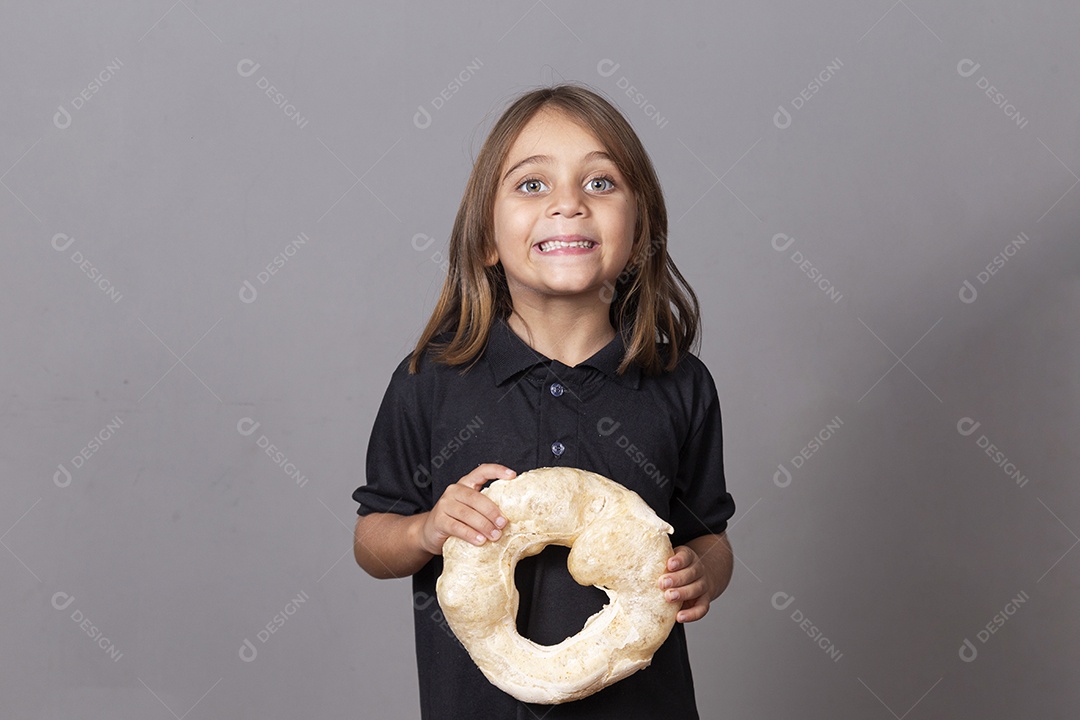 Crainça sorridente segurando biscoito rosca de polvilho sobre fundo isolado