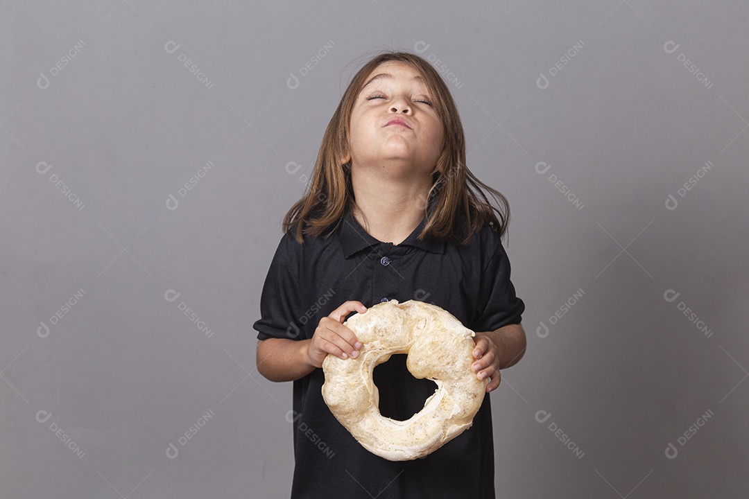 Criança segurando biscoito rosca de polvilho sobre fundo isolado