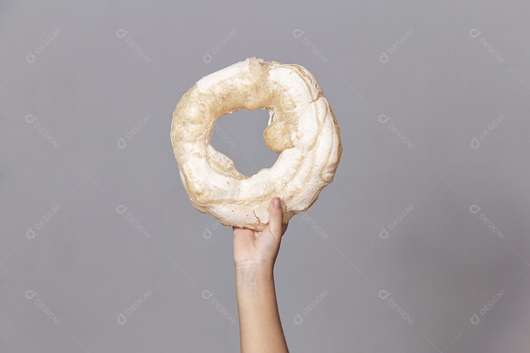Mão segurando biscoito rosca de polvilho sobre fundo isolado