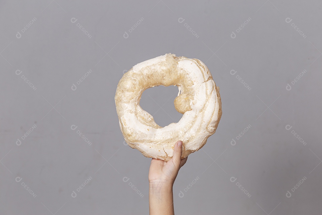 Mão segurando biscoito rosca de polvilho sobre fundo isolado