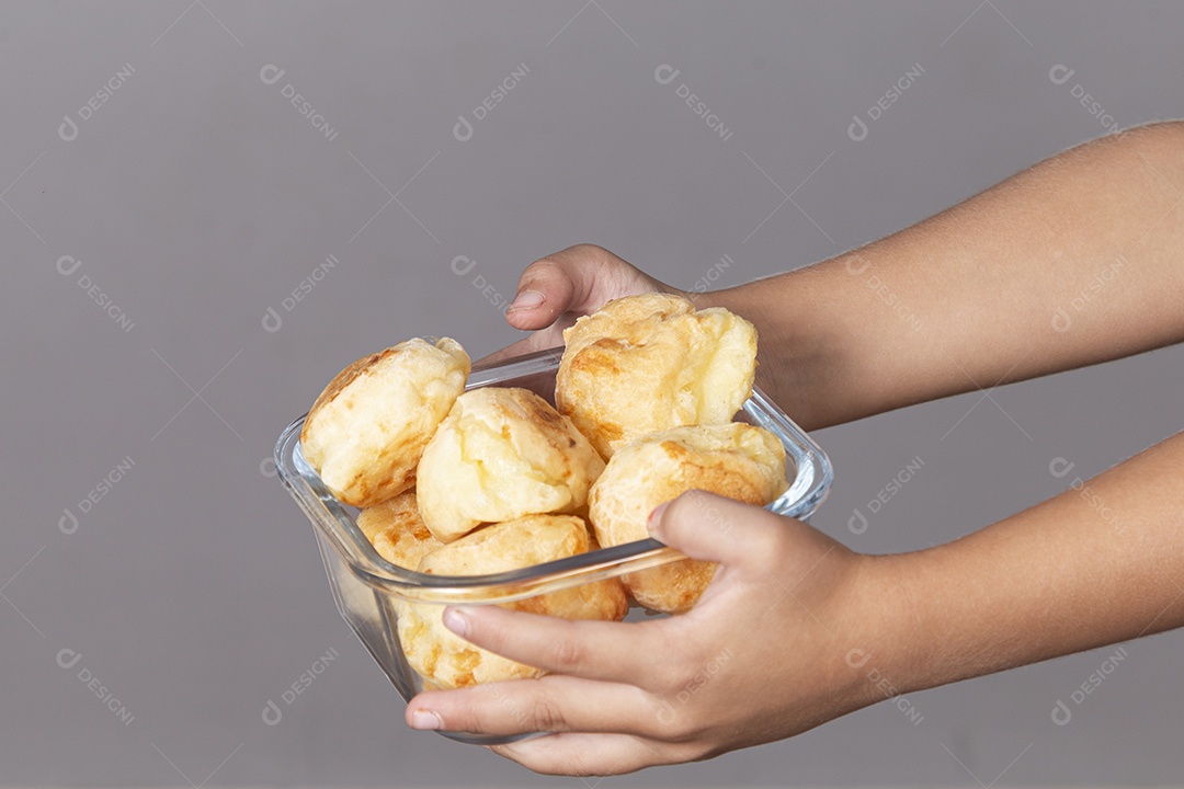 Mãos segurando travessa de pães de queijo sobre fundo isolado