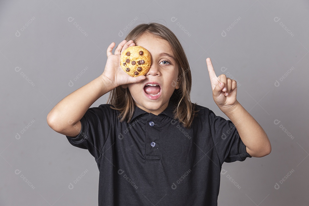 Garoto segurando bolacha sobre o olho