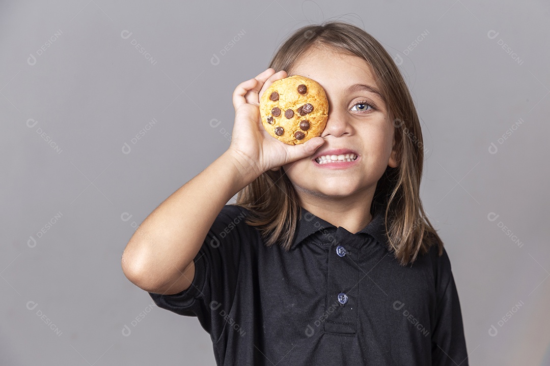 Garotinho segurando bolacha sobre um olho
