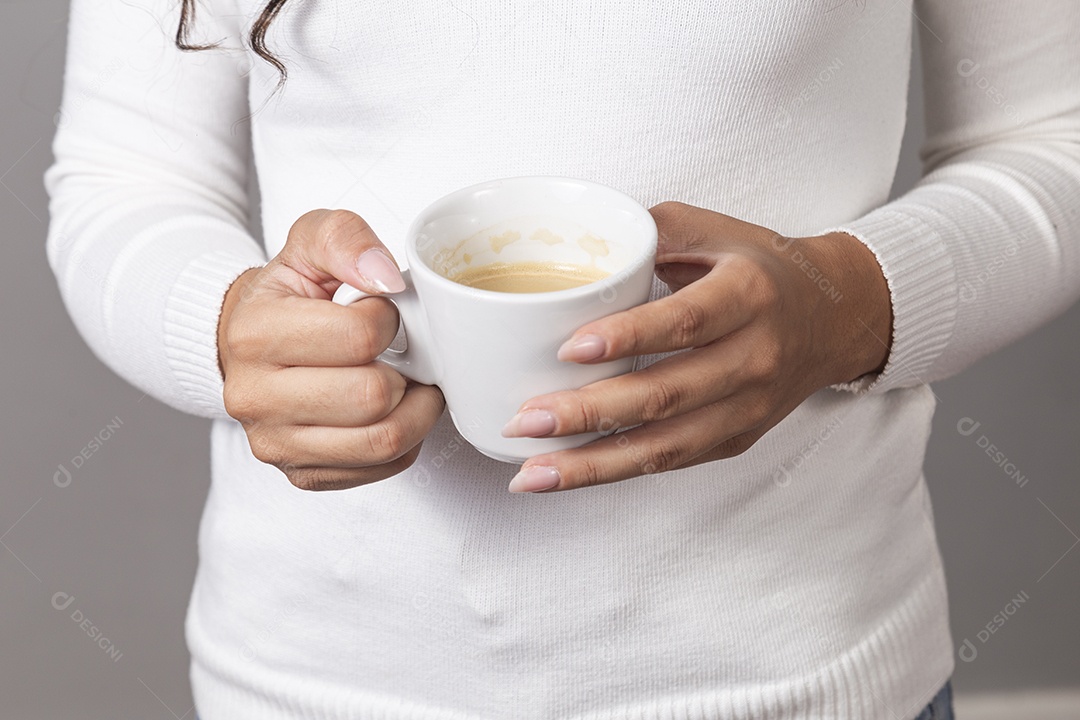 Mãos femininas segurando xícara branca sobre fundo isolado.