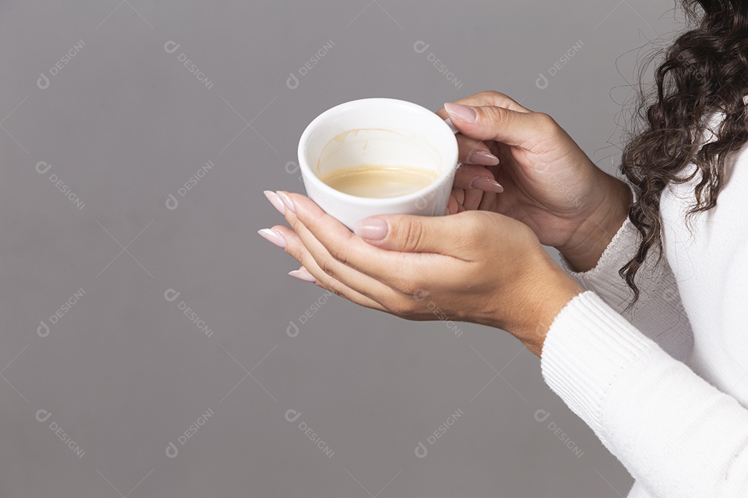 Mãos segurando xícara branca sobre fundo isolado.