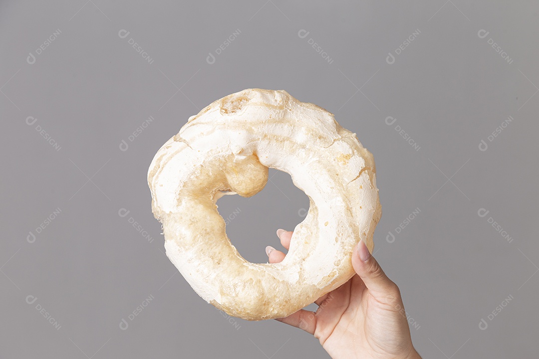 Mão segurando biscoito de polvilho sobre fundo isolado